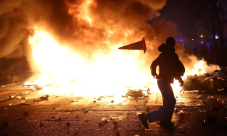 A man throws a plastic traffic cone through a burning barricade amid clashes during a day of demonstrations against the cost of living and rising fuel prices in Paris as part of nationwide protests called by the "Yellow Vests" movement, joined by French high school and university students, teachers and parents demanding better school conditions and government action, as well as labour unions, workers, farmers and retirees, France, October 17, 2026. REUTERS/Abdul Saboor TPX IMAGES OF THE DAY REFILE - CORRECTING ACTION FROM "A PROTESTERS SIT ON CHAIRS FROM A VANDALIZED SHOP AS THEY BLOCK A STREET" TO "A MAN THROWS A PLASTIC TRAFFIC CONE THROUGH A BURNING BARRICADE".