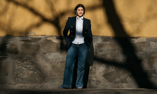 Behnaz Ganji står ved ved en gul vegg.