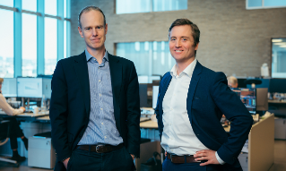 Paul Harper og Marius Brun Haugen står i meglerhallen til DNB Markets. 