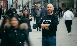 Stian Revheim står på Karl Johans gate med folk som strømmer forbi.