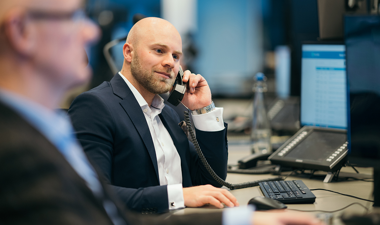 Trym Gjerstad Smedsrud prater i telefon på arbeidsplassen i Meglerhallen til DNB Markets. 