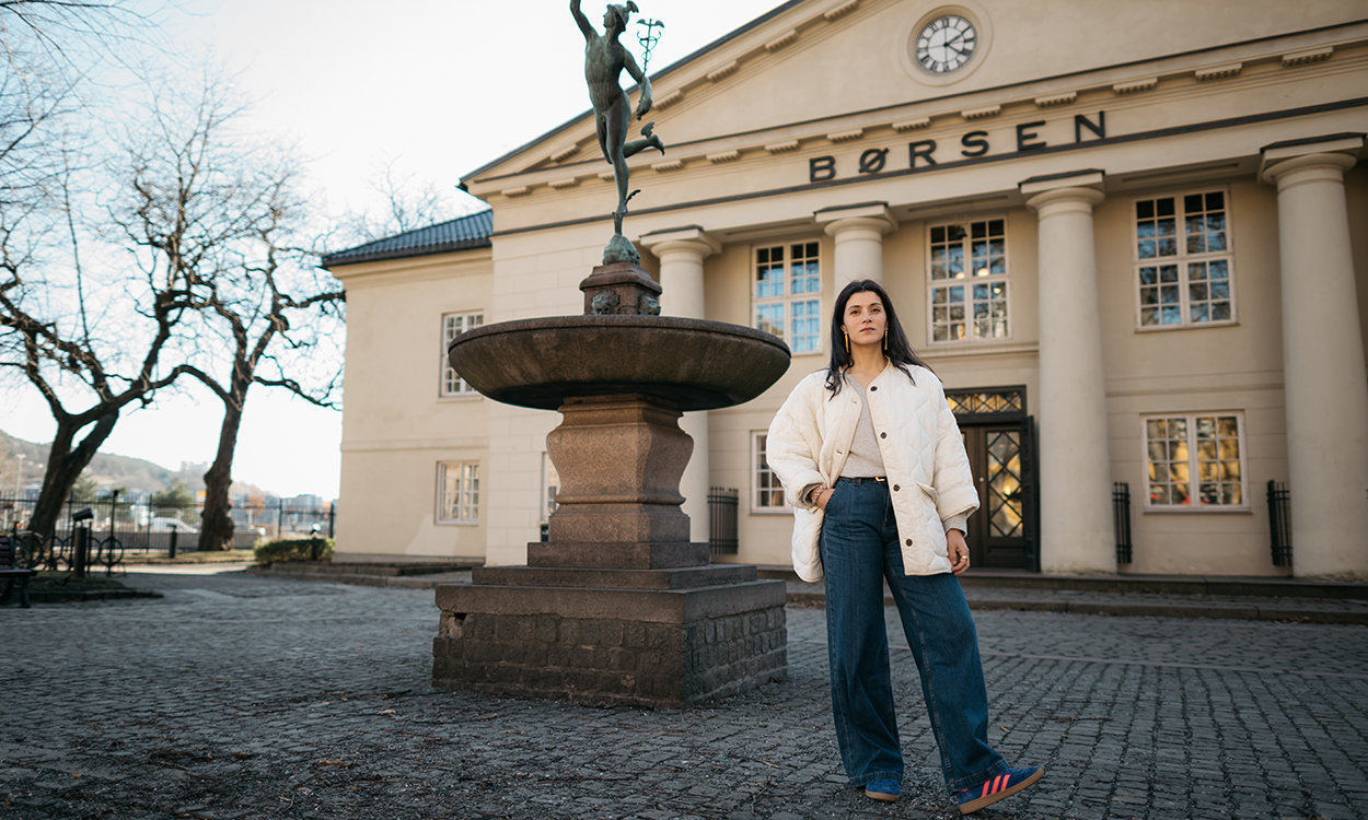 Behnaz Ganji står ved statuen Merkur ved Oslo Børs. 
