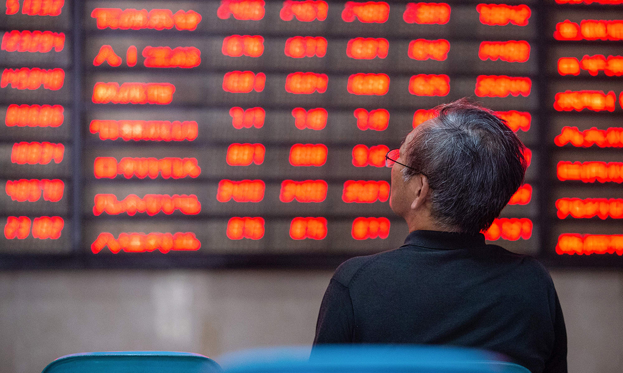 An investor looks at screens showing stock market movements at a securities company in Nanjing in China's eastern Jiangsu province on July 6, 2020. - Shanghai stocks surged on July 6 to a more than two-year high as investors piled in following a combination of rosy predictions for the market and strong economic data. (Photo by STR / AFP) / China OUT