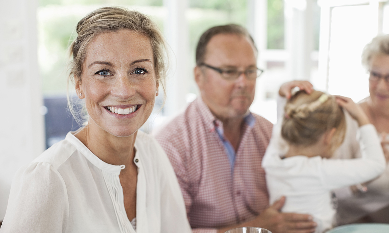Portrait of smiling woman sitting at dining table with family