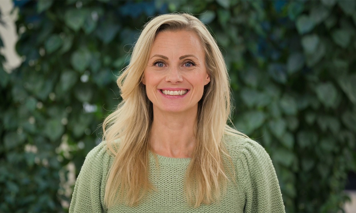 Silje Sandmæl ser i kameraet og smiler. Hun har på seg en grønn genser. 