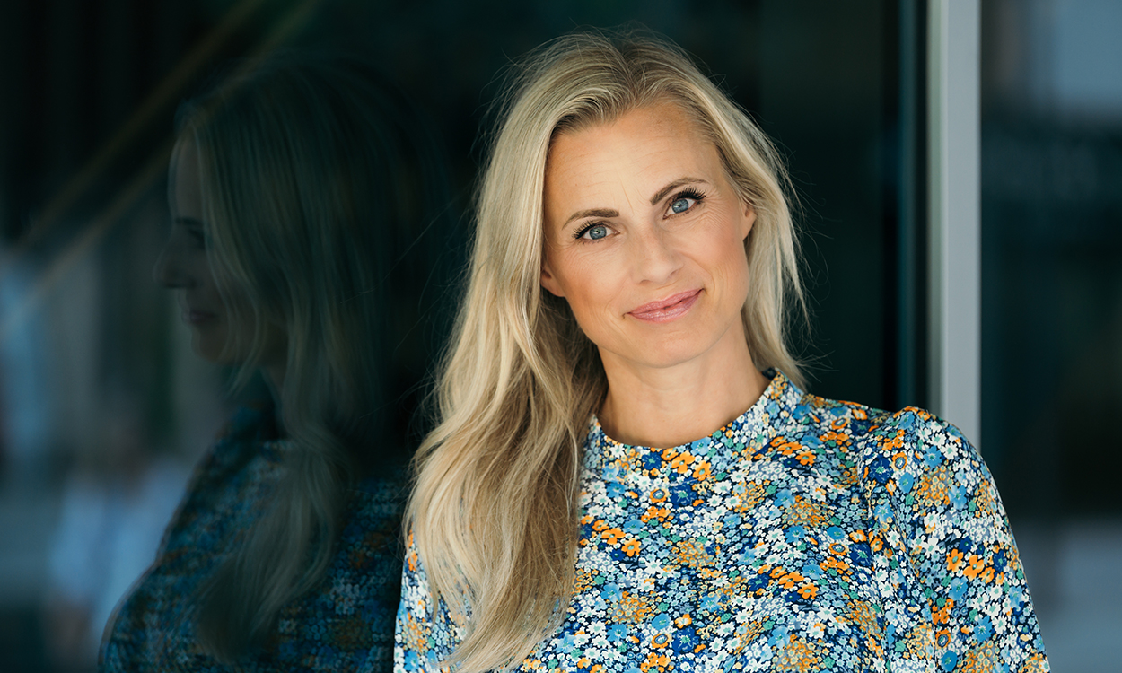 Silje Sandmæl står ute ved en glassfasade. 
