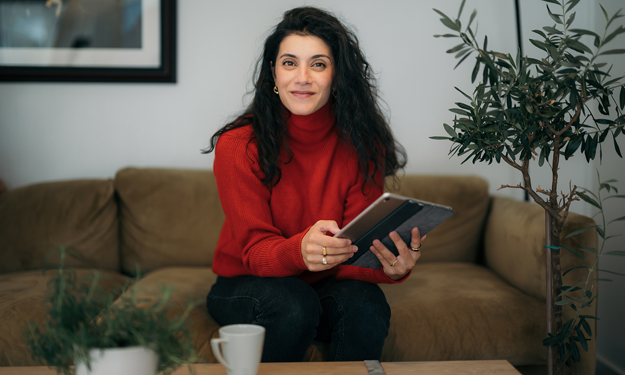 Behnaz Ganji sitter i sofaen med en ipad. 