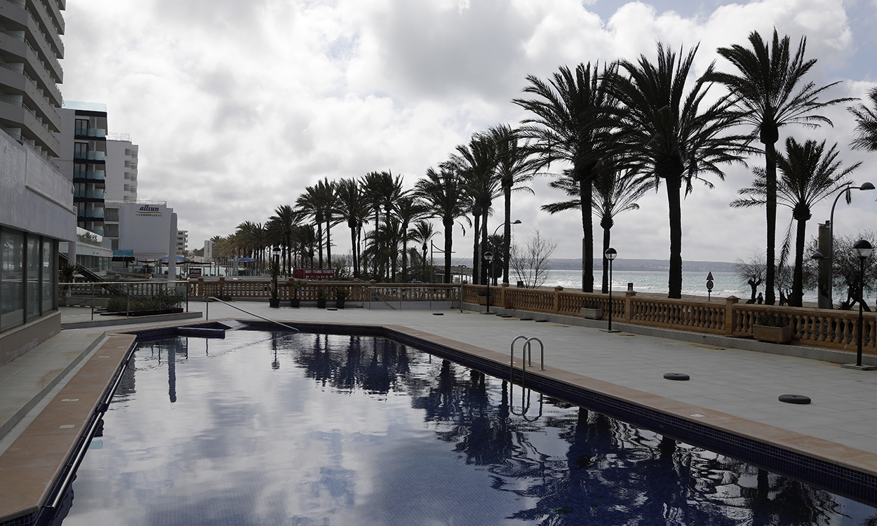 11 March 2021, Spain, Palma: Palm trees are reflected in the pool of a closed hotel on the beach of Arenal. German tour operators hope that they can bring holidaymakers back to Mallorca from the Easter holidays. Photo: Clara Margais/dpa - ATTENTION: Names on the tubes have been pixelated for legal reasons