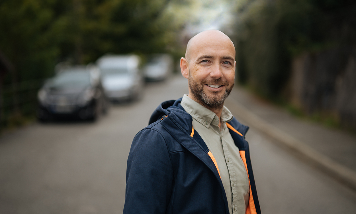 Stian Revheims står i en bergensgate med biler og trær. 
