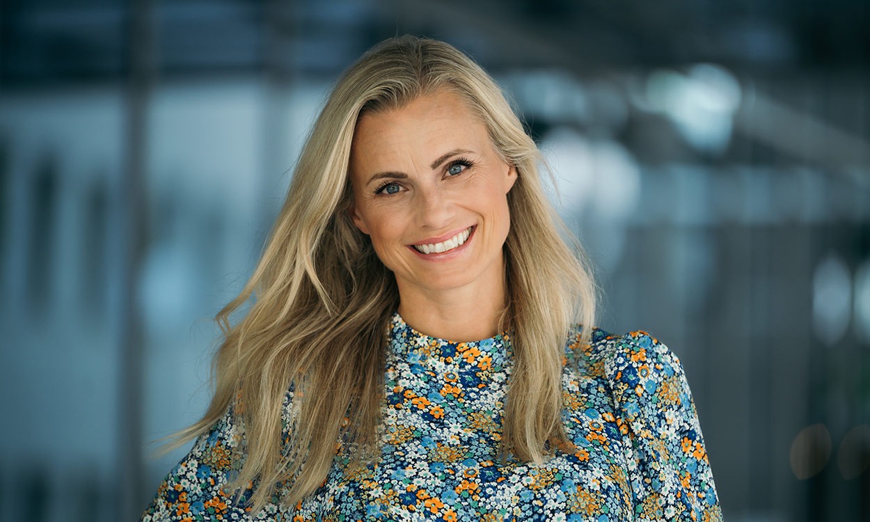 Silje Sandmæl står ute ved en glassfasade. 