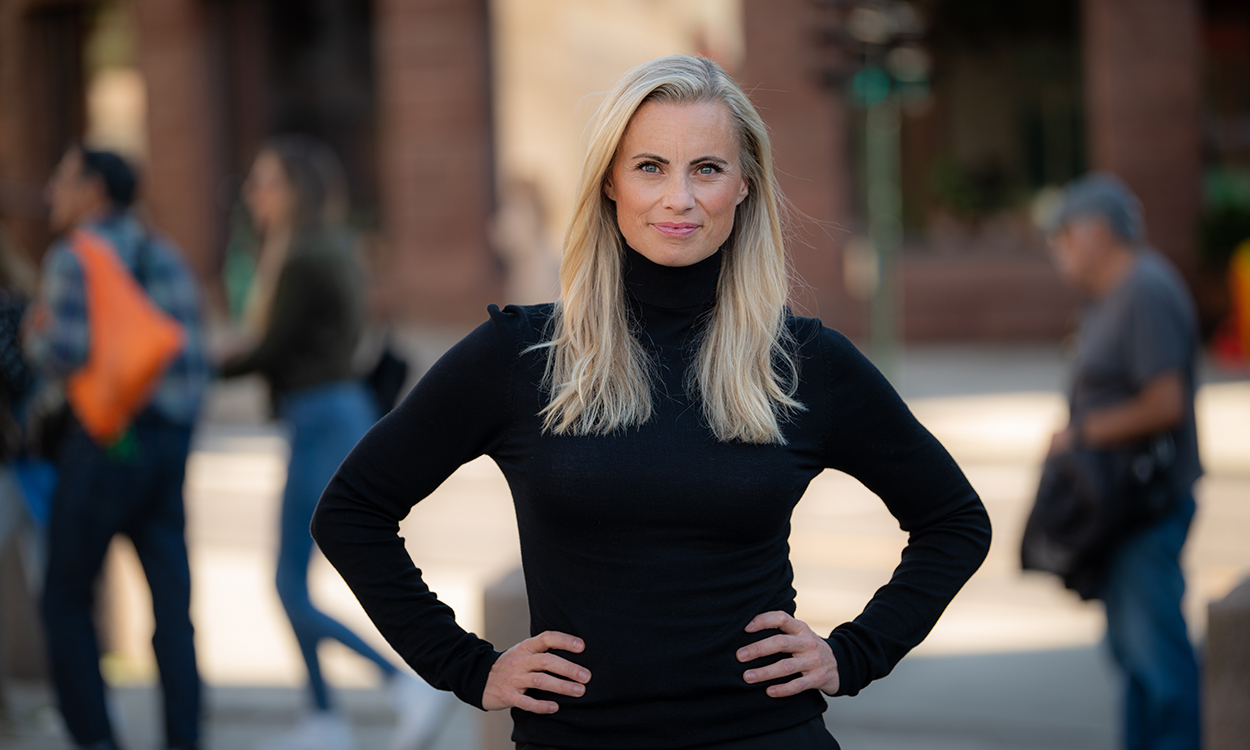 Silje Sandmæl står i gaten, mens folk passerer forbi. 