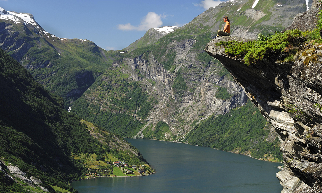 Woman sitting on a ledge, Geiranger Fjord, Hellesylt, More og Romsdal, Norway, Europe