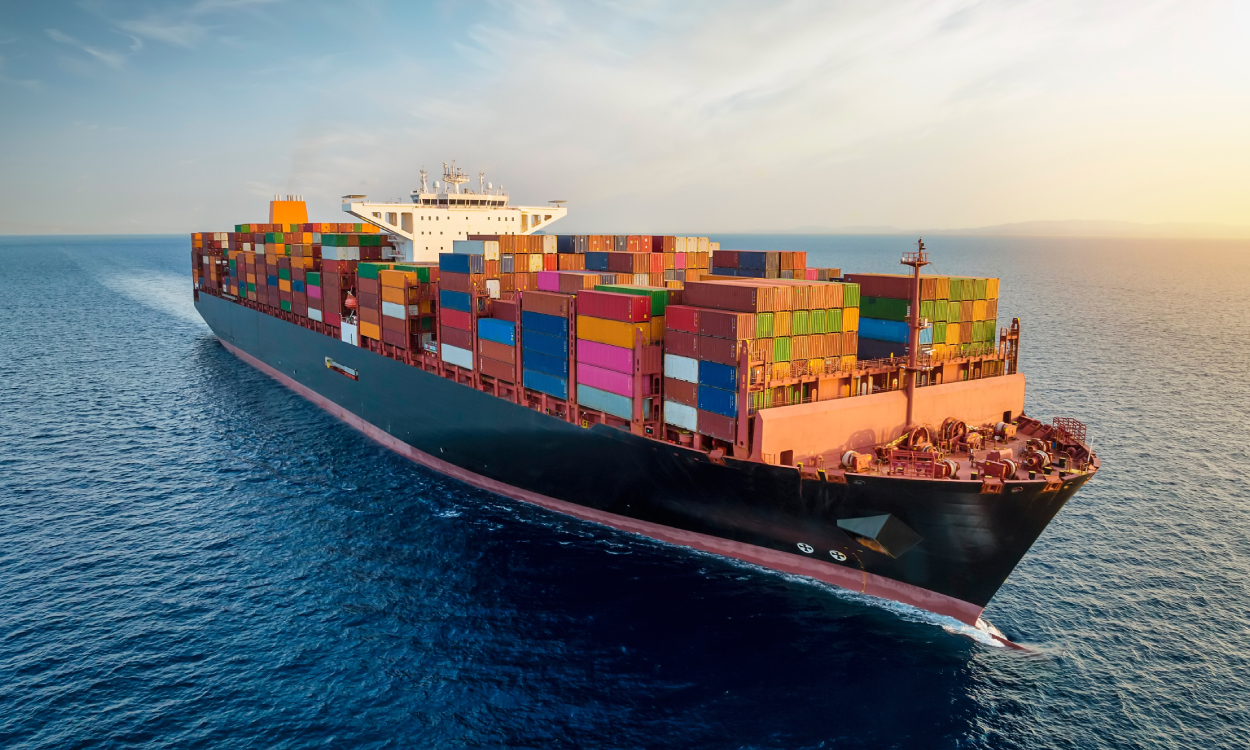 Aerial view of a large, loaded container cargo ship traveling over open ocean