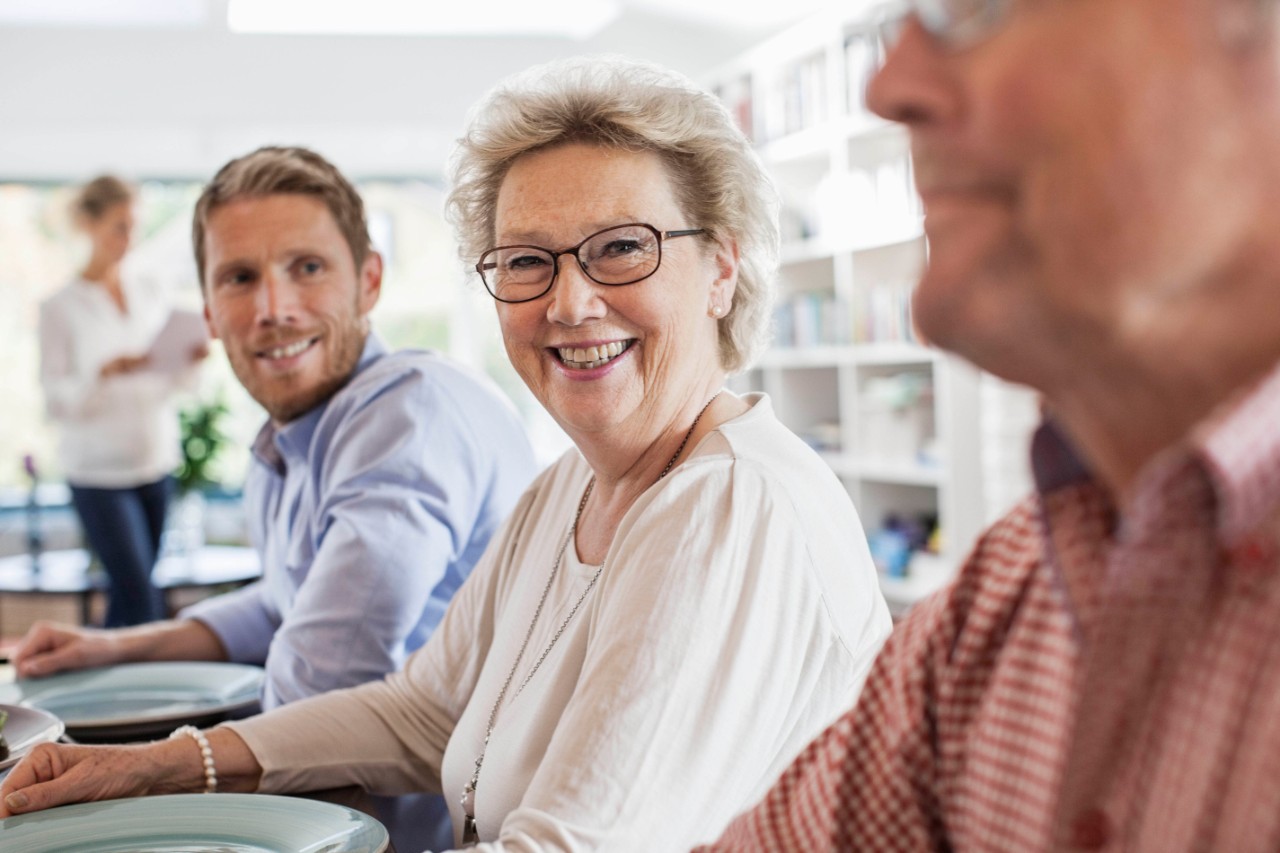 Portrait of happy senior woman sitting with family at dining table