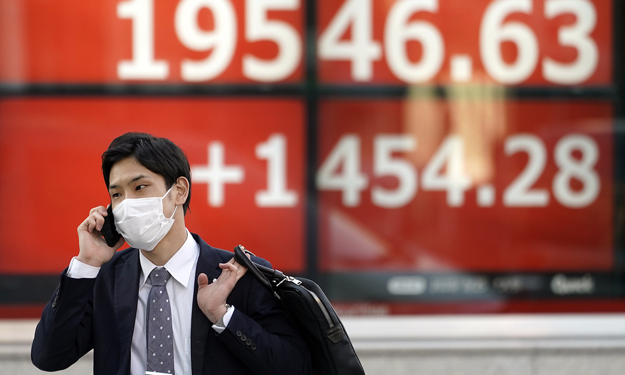  A pedestrian wearing a mask walks before a stock market indicator board in Tokyo, Japan, 25 March 2020. The Nikkei Stock Average soared by 1,454.28 points, up 8.04 per cent, to close at 19,546.63, following large overnight gains in Wall Street.  EPA/FRANCK ROBICHON
